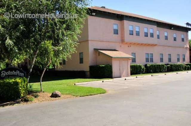 Large apartment block with 10 large windows facing Ample exterior parking. Concrete construction is painted pink. 